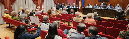 Momento en el que algunos asistentes levantan carteles contra las plantas de biometano antes de finalizar la sesión plenaria de octubre
